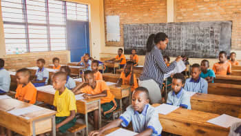 Teacher in a Rwandan classroom handing out assessments to students