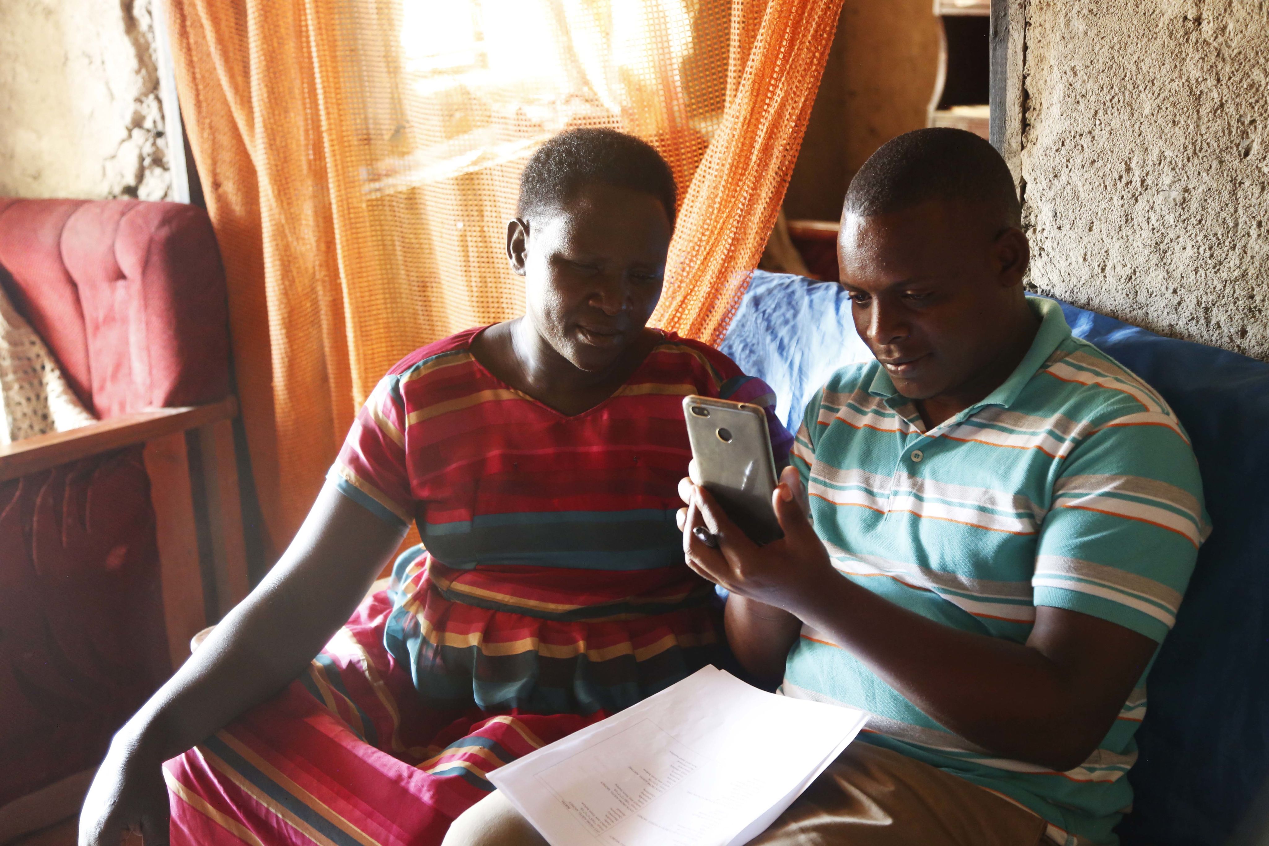 An IPA enumerator (right) shows a faith leader how to use a smartphone for the Becoming One program. © 2018 Aude Guerrucci