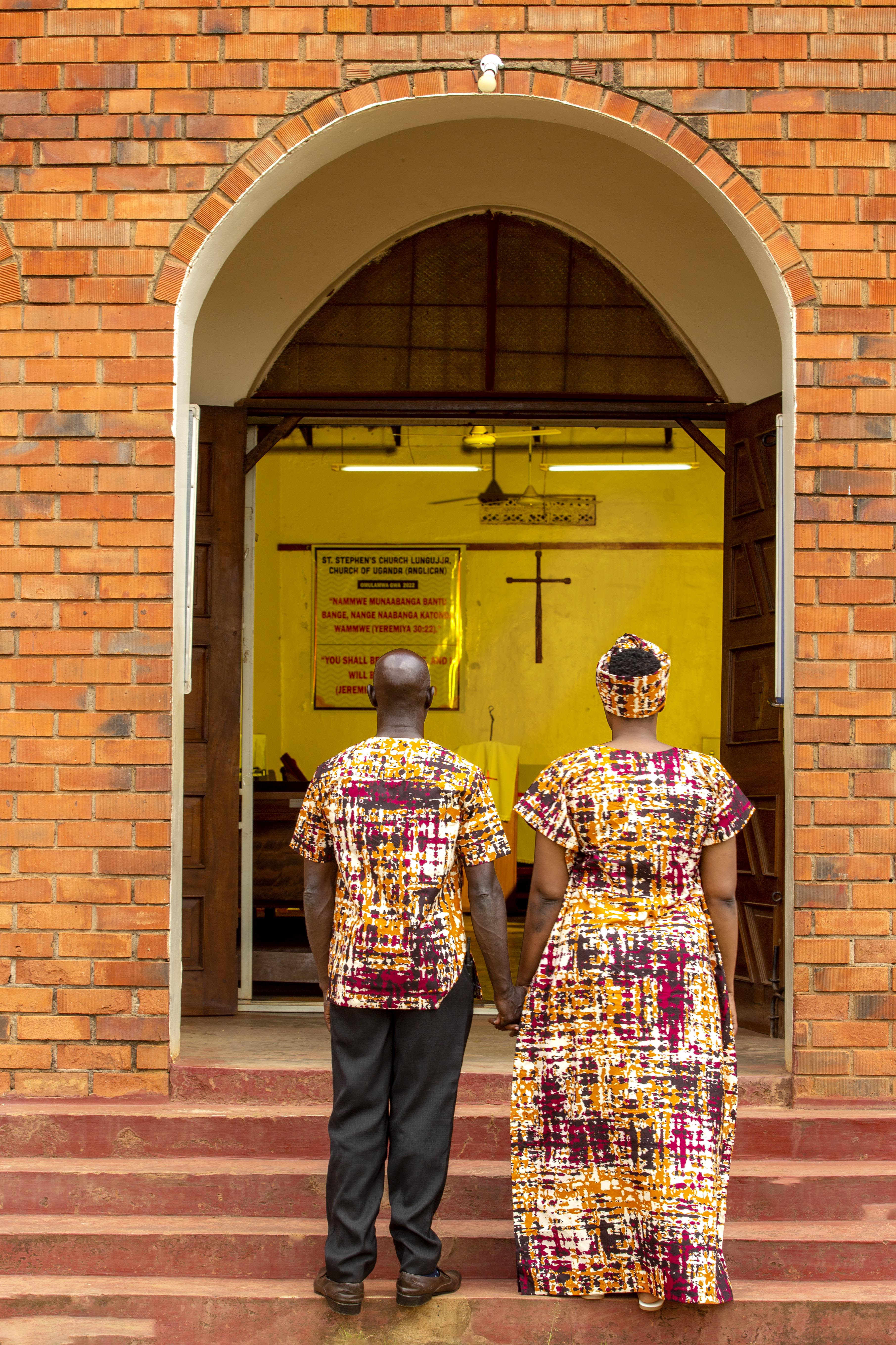 A man and a woman standing holding hands in front of the entrance to a church