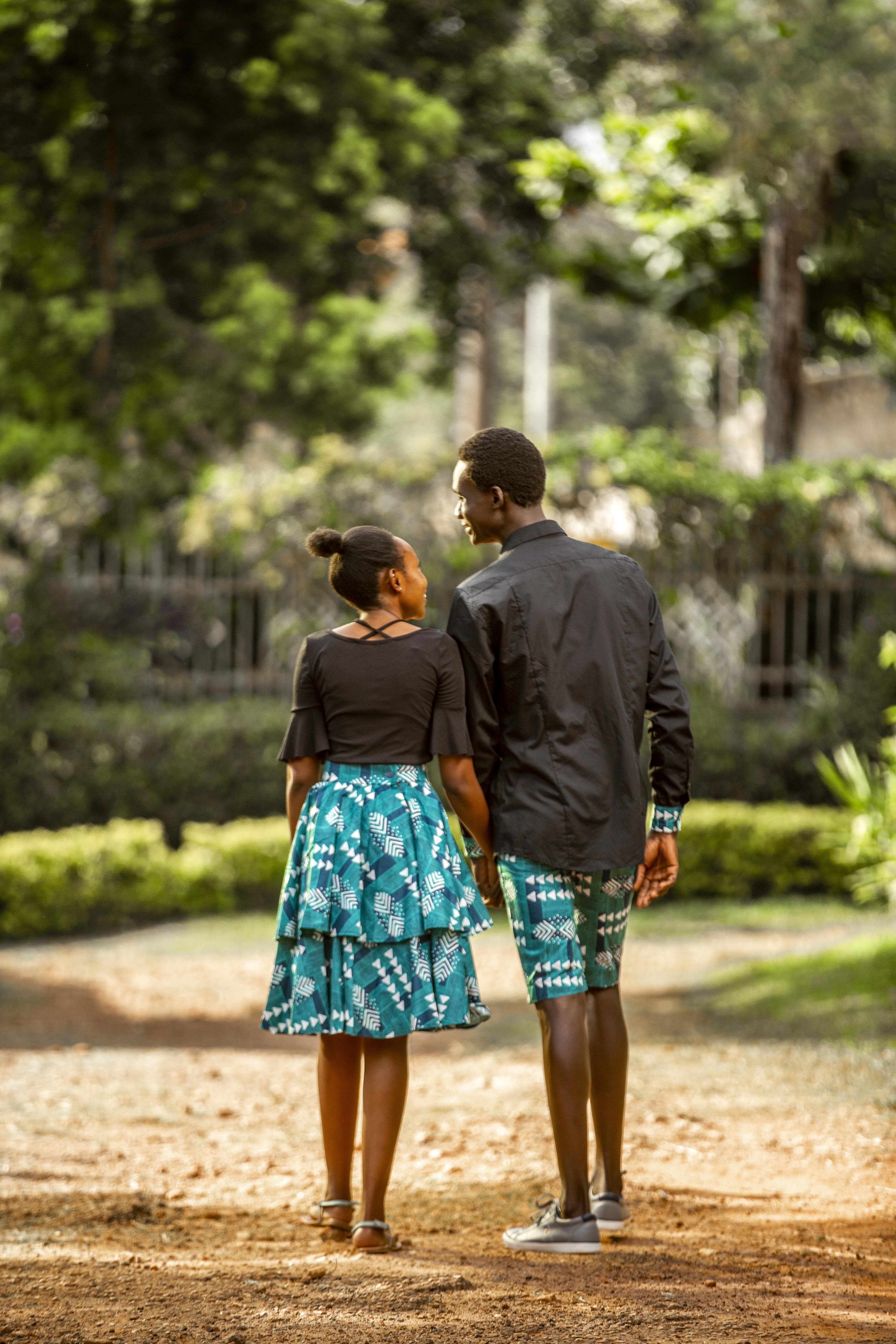 A couple holding hands standing outside surrounded by trees